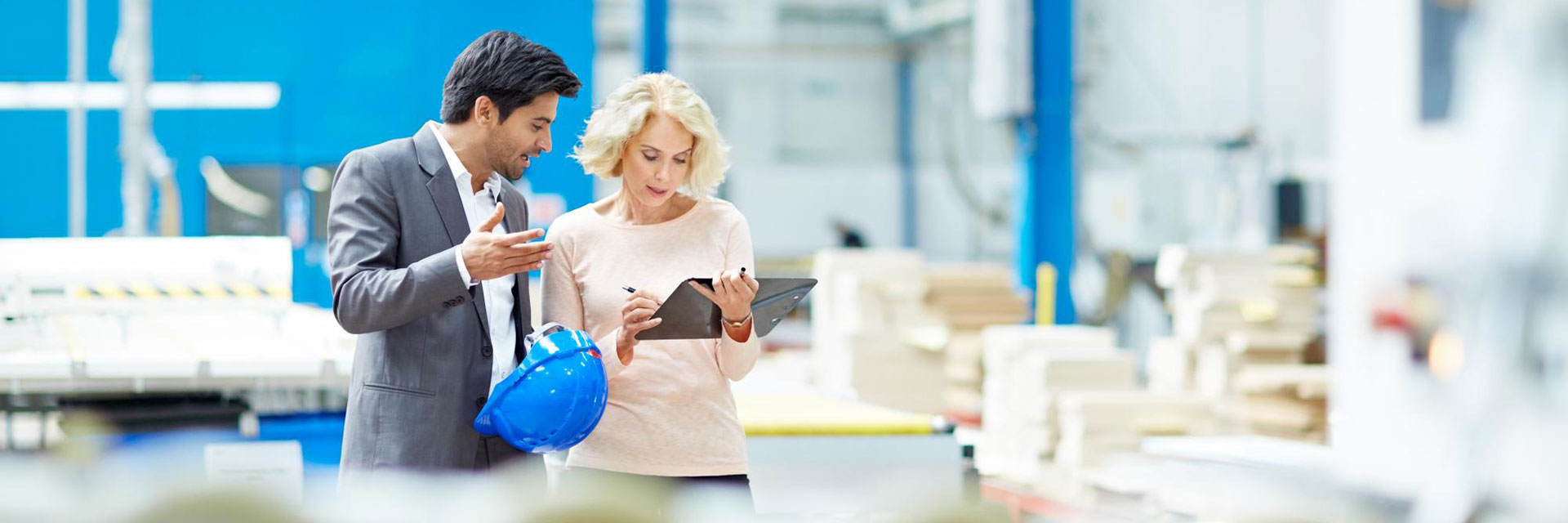A man and a woman review work on a tablet in a high quality filtration solutions plant.